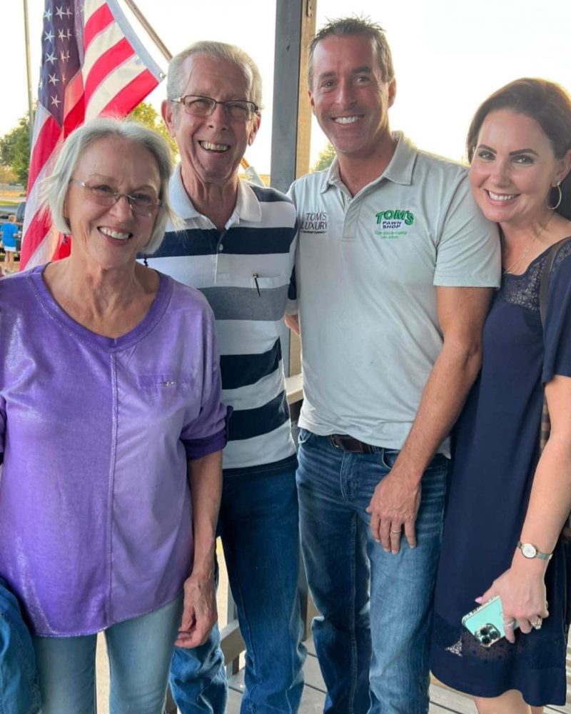 Tom's Sport Shop - A group of people posing for a photo with an American flag.
